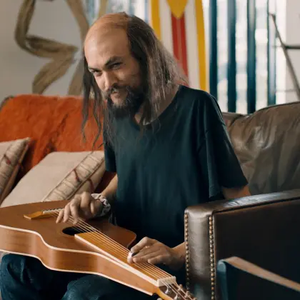 Jason Momoa looking very slim holding guitar