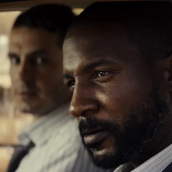 Two agents in the car looking out of the car window